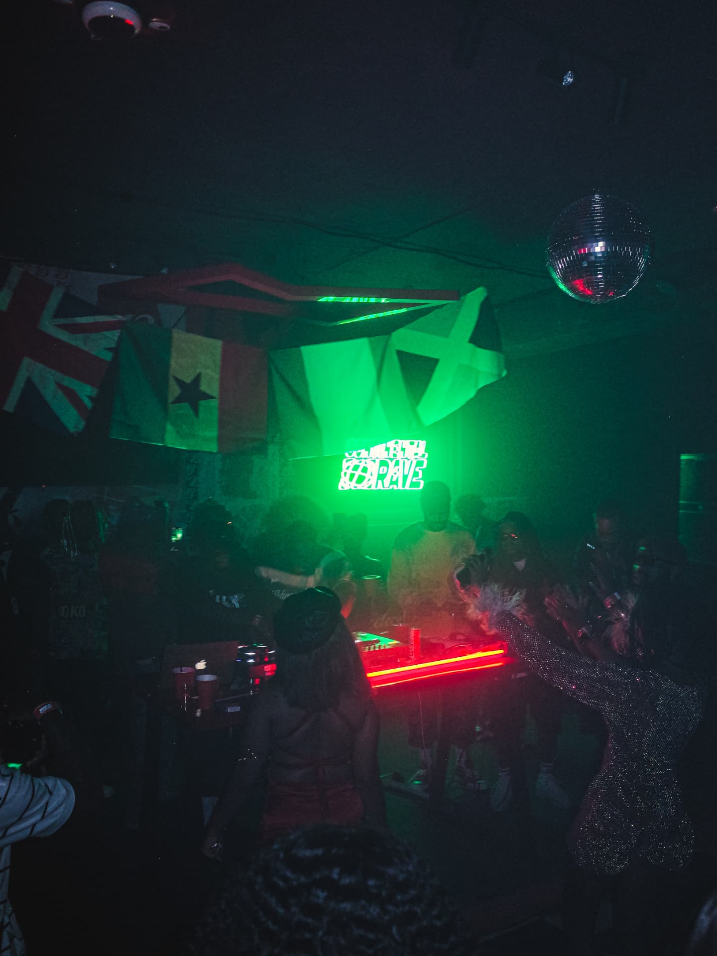 Continental Rave DJ booth under the neon sign, hanging flags and a disco ball